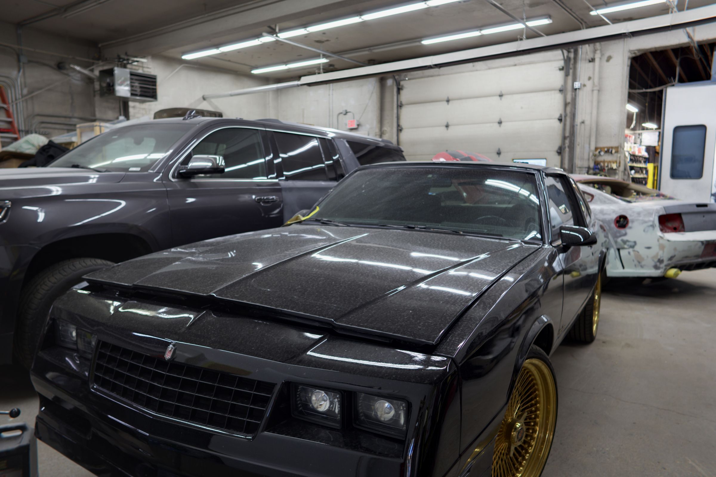 A black classic Monte Carlo on gold wheels inside the O'Keeffe's Collision shop